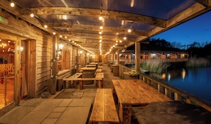 An outdoor wooden deck with tables and benches, overlooking a body of water. - Silverwood Resort & events Barn  (Perth)