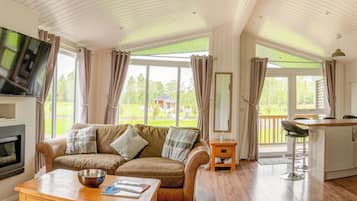 Una sala de estar acogedora con chimenea, un sofá, una mesa de centro y un televisor.