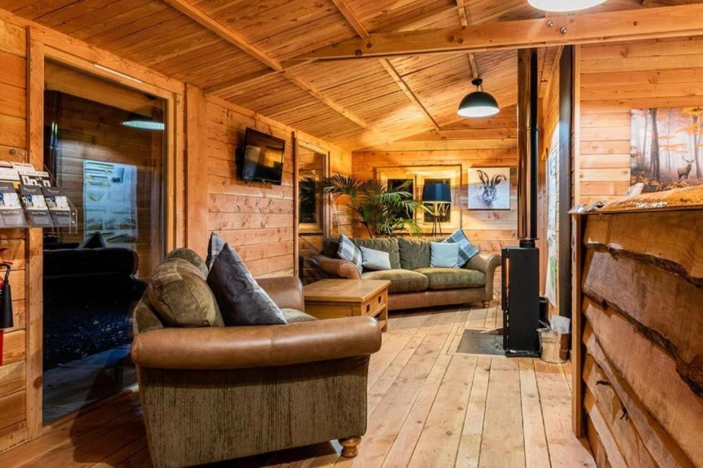 A wooden cabin interior with a sofa, a table, and a fireplace.