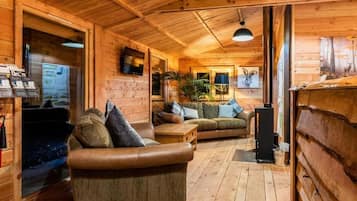 A wooden cabin interior with a sofa, a table, and a fireplace.