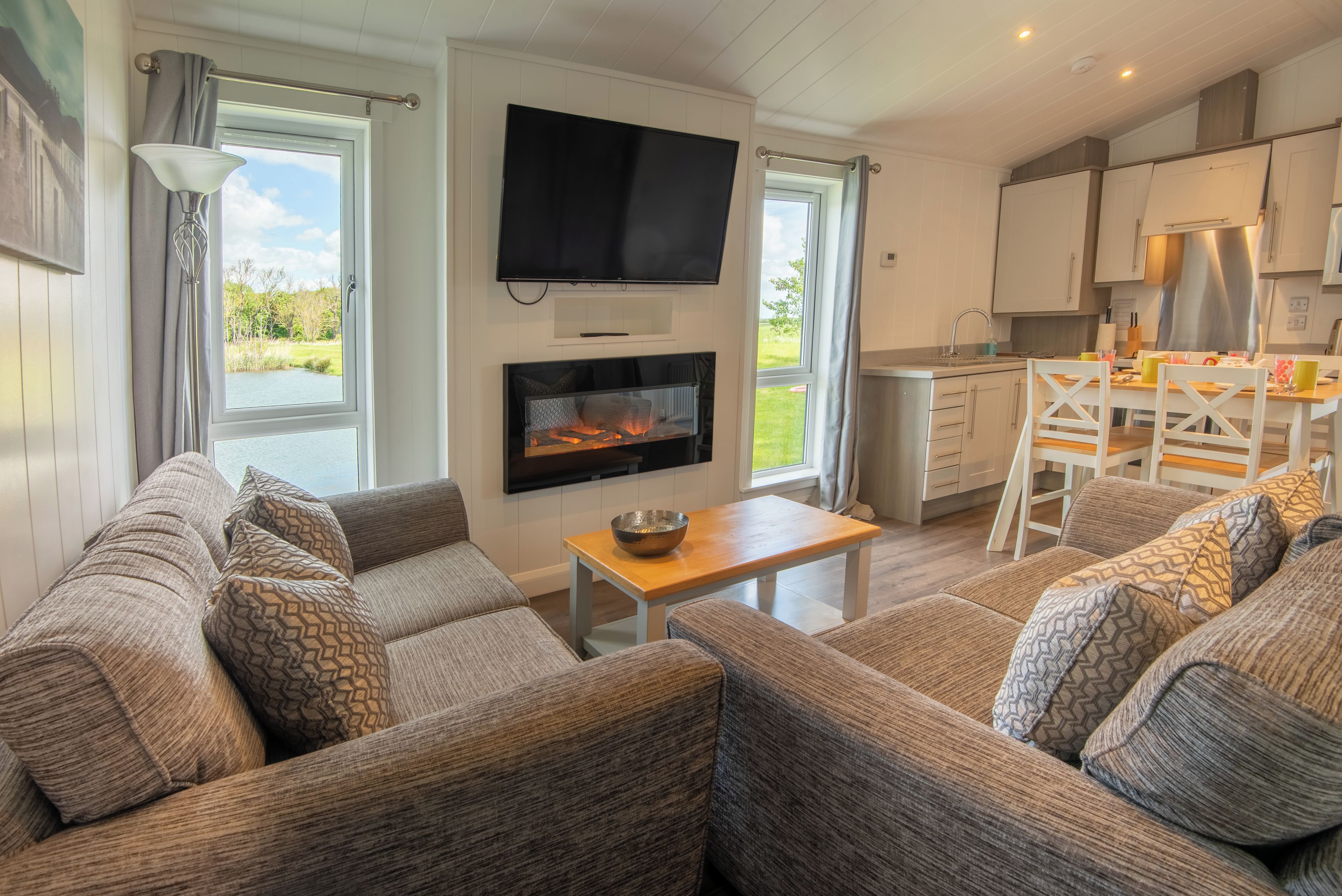 Ein möbliertes Wohnzimmer mit Kamin, Fernseher und Blick ins Freie.