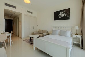 Una habitación de hotel con cama, sofá, mesa de comedor y un cuadro en la pared.