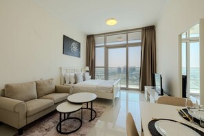 Una habitación de hotel moderna con cama, sofá, mesa de comedor y televisor.