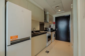Cocina compacta con refrigerador, estufa, pileta y microondas.
