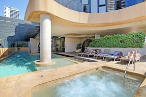 Ein Poolbereich mit Liegestühlen und einem Whirlpool.