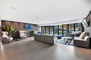 A modern living room with a flat-screen TV, comfortable seating, and a view of the outdoors. - Jewel 27 Luxury 5 Star Beachfront King & Queen (Surfers Paradise)