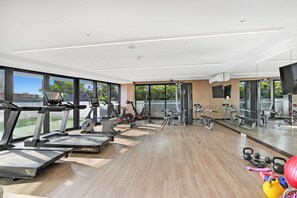 Ein modernes Fitnessstudio mit Cardiogeräten, Kurzhanteln und Spiegeln.