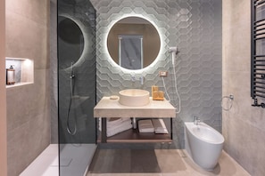 A modern bathroom with a glass-enclosed shower, a round sink with a mirror, and a bidet. - AF Luxury Rooms (Rome)