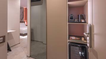 Quarto de hotel com minibar, cafeteira e frigorífico.