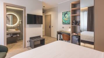 Ett modernt hotellrum med en stor säng, ett skrivbord, en tv, ett badrum med spegel och handfat samt en tavla på väggen.