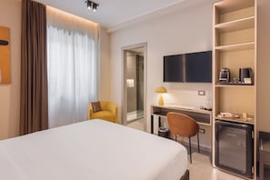 A hotel room with a bed, a desk, a chair, a TV, and a minibar. - AF Luxury Rooms (Rome)