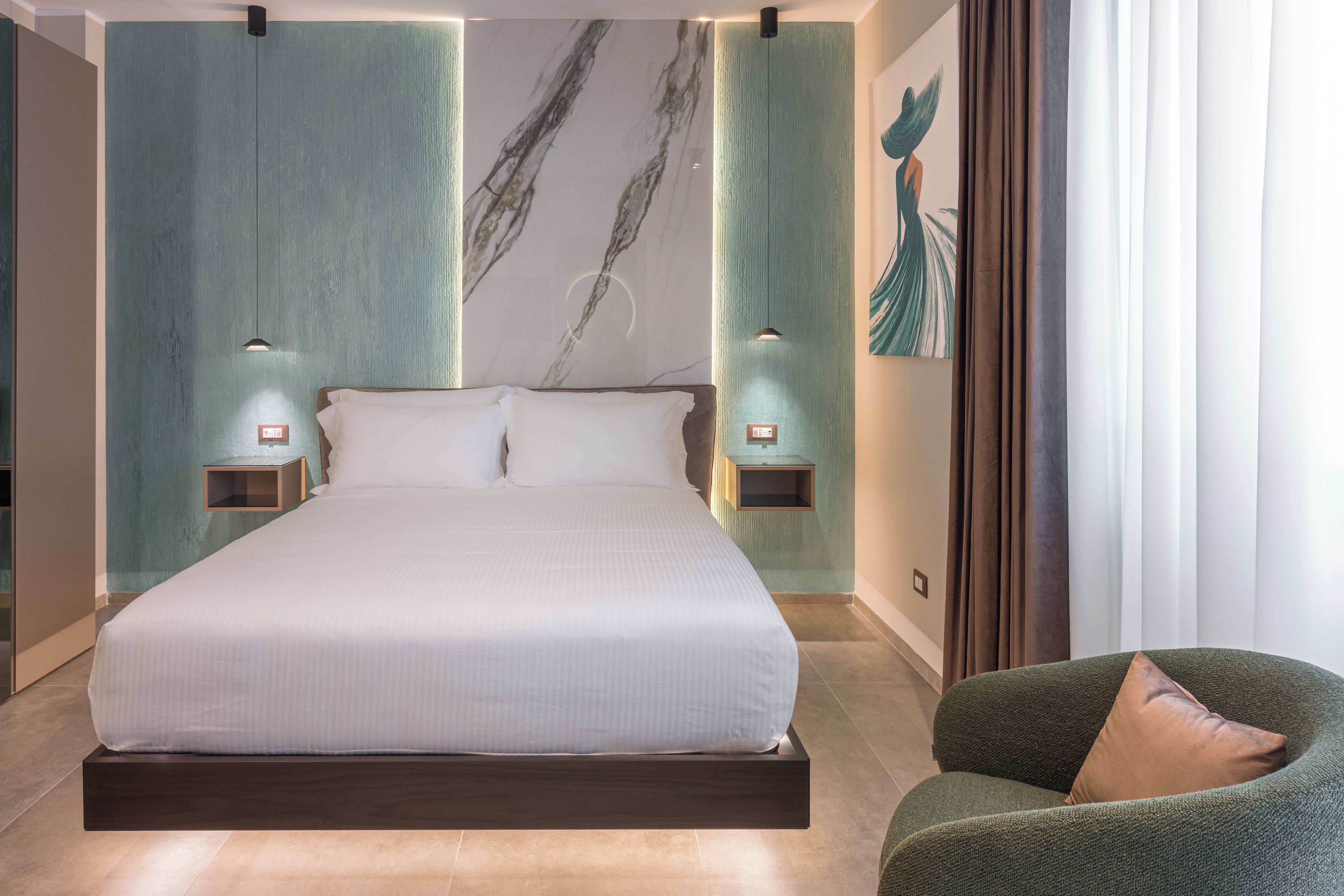 A modern bedroom with a large bed, two bedside tables, and a green armchair.