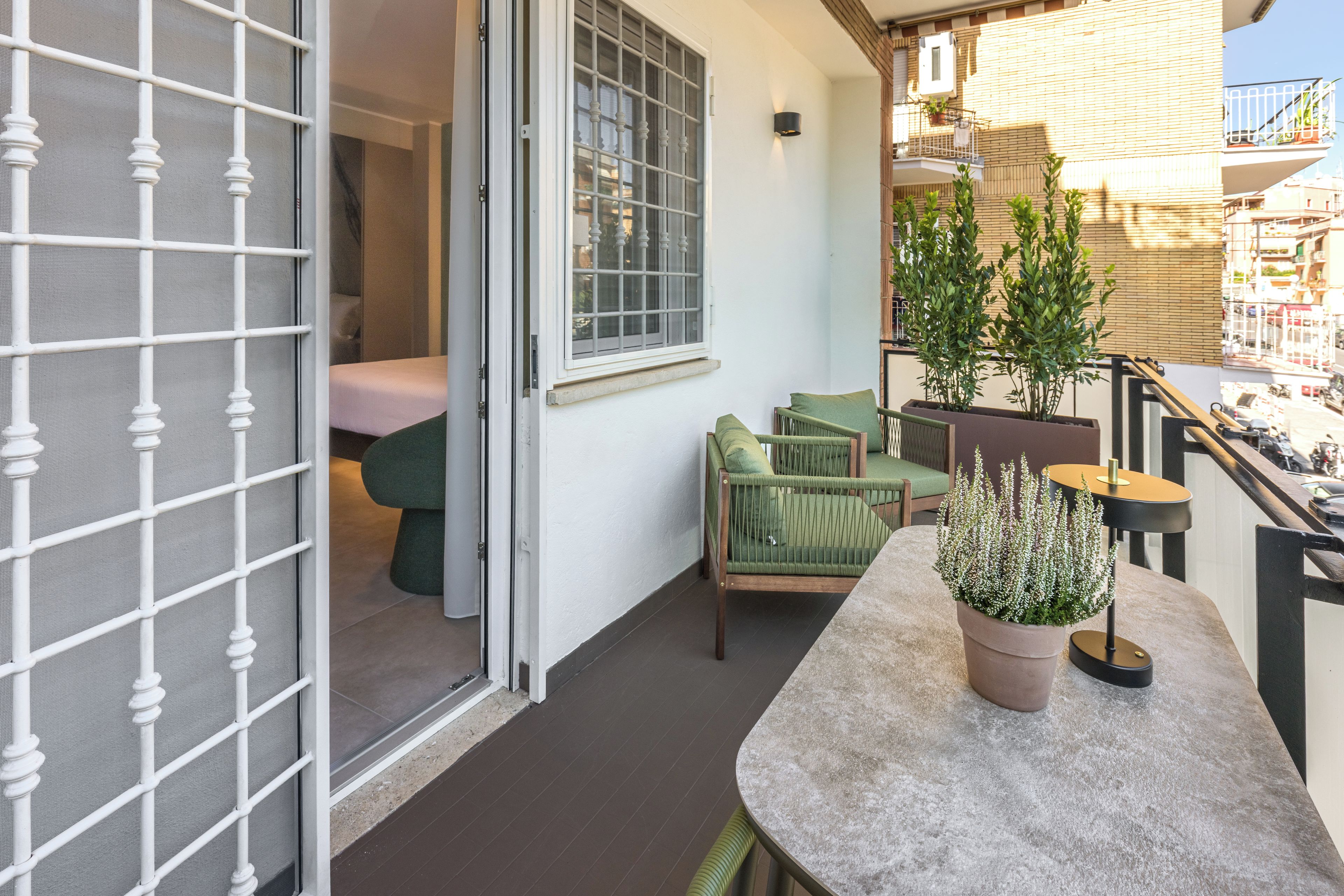 A balcony with a seating area, a potted plant, and a view of the street.