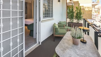 A balcony with a seating area, a potted plant, and a view of the street.
