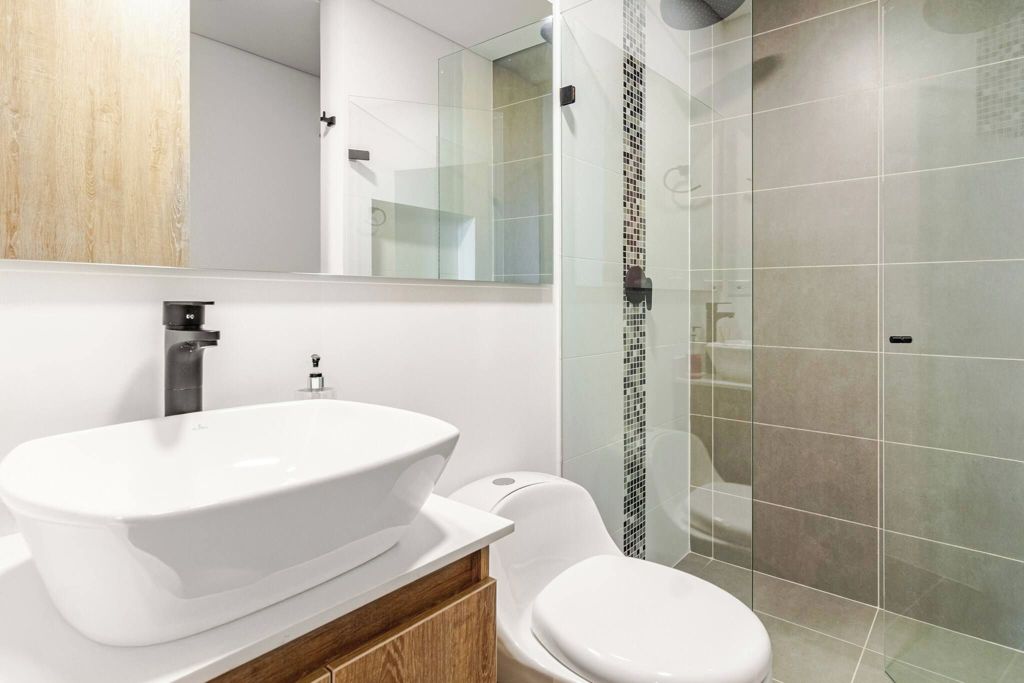 Un baño moderno con un lavamanos independiente, un inodoro y una cabina de ducha de vidrio.