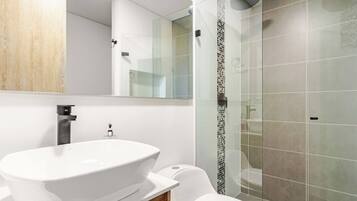 Un baño moderno con un lavamanos independiente, un inodoro y una cabina de ducha de vidrio.
