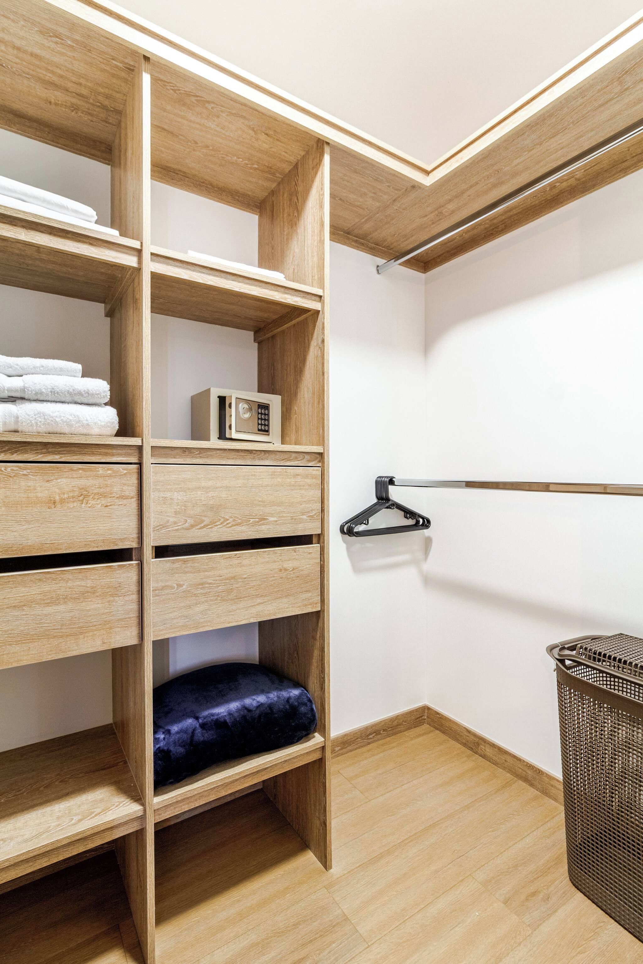 A walk-in closet with wooden shelving, a hanging rod, and a storage basket.