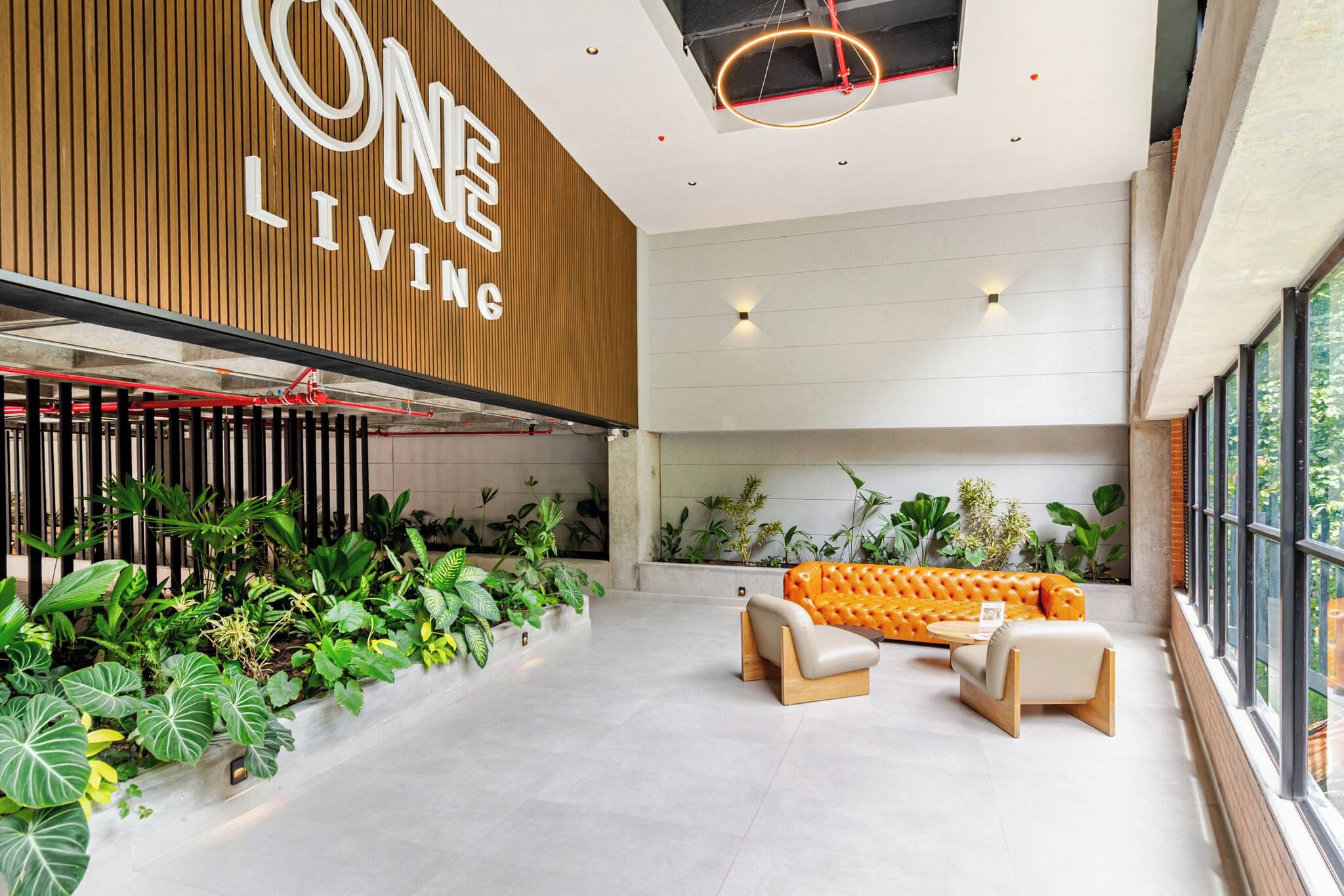 Un interior moderno con una pared de madera que muestra 'ONE LIVING' y una zona de estar con un sofá y sillones.
