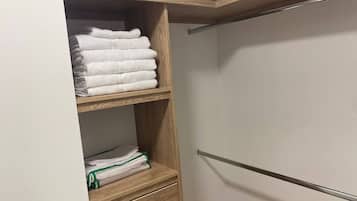 Un armario con estantes y cajones de madera, que contiene toallas dobladas y una bolsa verde.