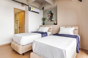 Ein Hotelzimmer mit zwei Betten, einer Decken-Klimaanlage, einer Tür und einem Wandbild.