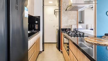 Una cocina compacta equipada con refrigerador, estufa y lavamanos.