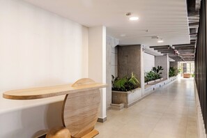 Ein modernes Interieur mit einer Holzbank, Betonpfeilern und Topfpflanzen.
