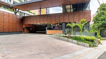 A modern building with a covered entrance, a brick facade, and a landscaped area with plants.