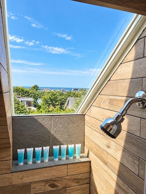 A bathroom with a skylight, a showerhead, and a shelf with skincare products. - Gatsby’s OBP, 3rd House to the Beach, Heated Pool + 2 Hot Tubs, Sleeps 24 (Ocean Bay Park)