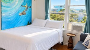 A bedroom with a bed, a ceiling fan, a painting, a window with curtains, and a view of the outside. - Gatsby’s OBP, 3rd House to the Beach, Heated Pool + 2 Hot Tubs, Sleeps 24 (Ocean Bay Park)