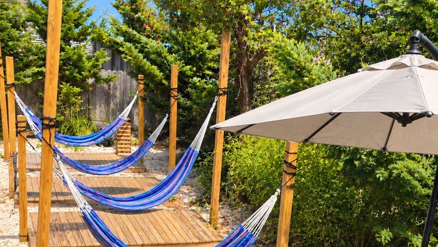 A wooden deck with a grill, a hammock, and a table with chairs. - Gatsby’s OBP, 3rd House to the Beach, Heated Pool + 2 Hot Tubs, Sleeps 24 (Ocean Bay Park)