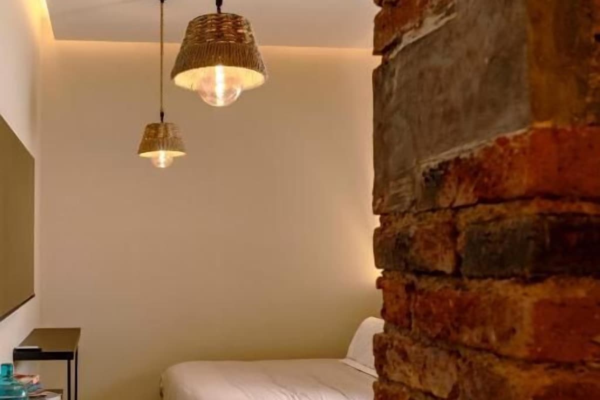 Una habitación con dos camas, una pared de ladrillo y lámparas colgantes.