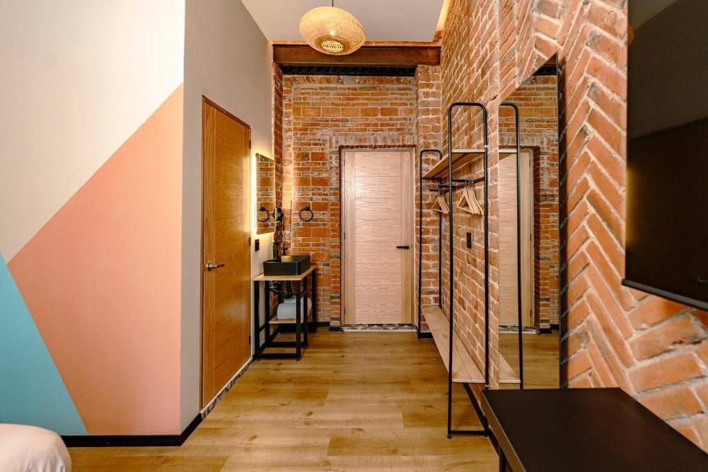 A hallway with a brick wall, a wooden door, and a bench.