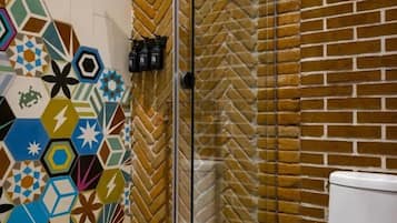 Un bagno con doccia, WC e parete rivestita di piastrelle esagonali colorate.