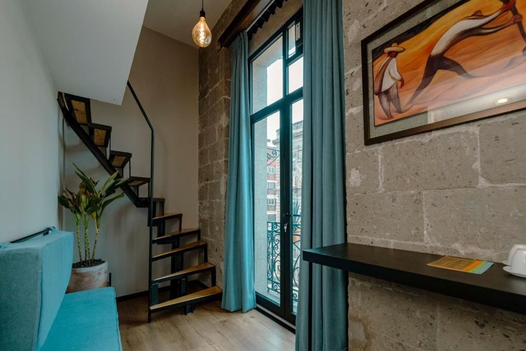 A staircase with a potted plant, a framed artwork, and a window with curtains.