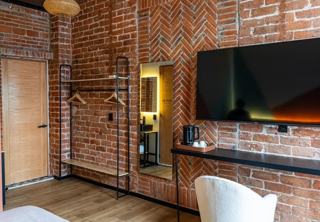 Een kamer met een bakstenen muur, een houten deur, een spiegel, een televisie en een salontafel.