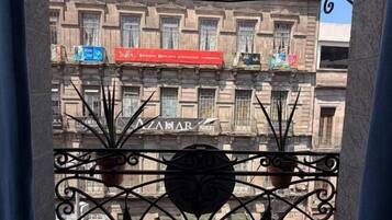 Un balcón con barandillas de hierro forjado decoradas y vistas a un edificio con varios balcones y letreros.