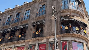 Un edificio con varios balcones, algunos con plantas en macetas, y locales comerciales con la marca Coca-Cola.
