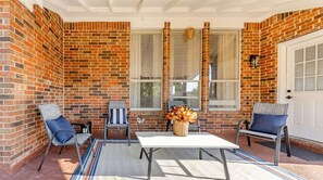 Un patio cubierto con paredes de ladrillo, una mesa, sillas y un jarrón decorativo.