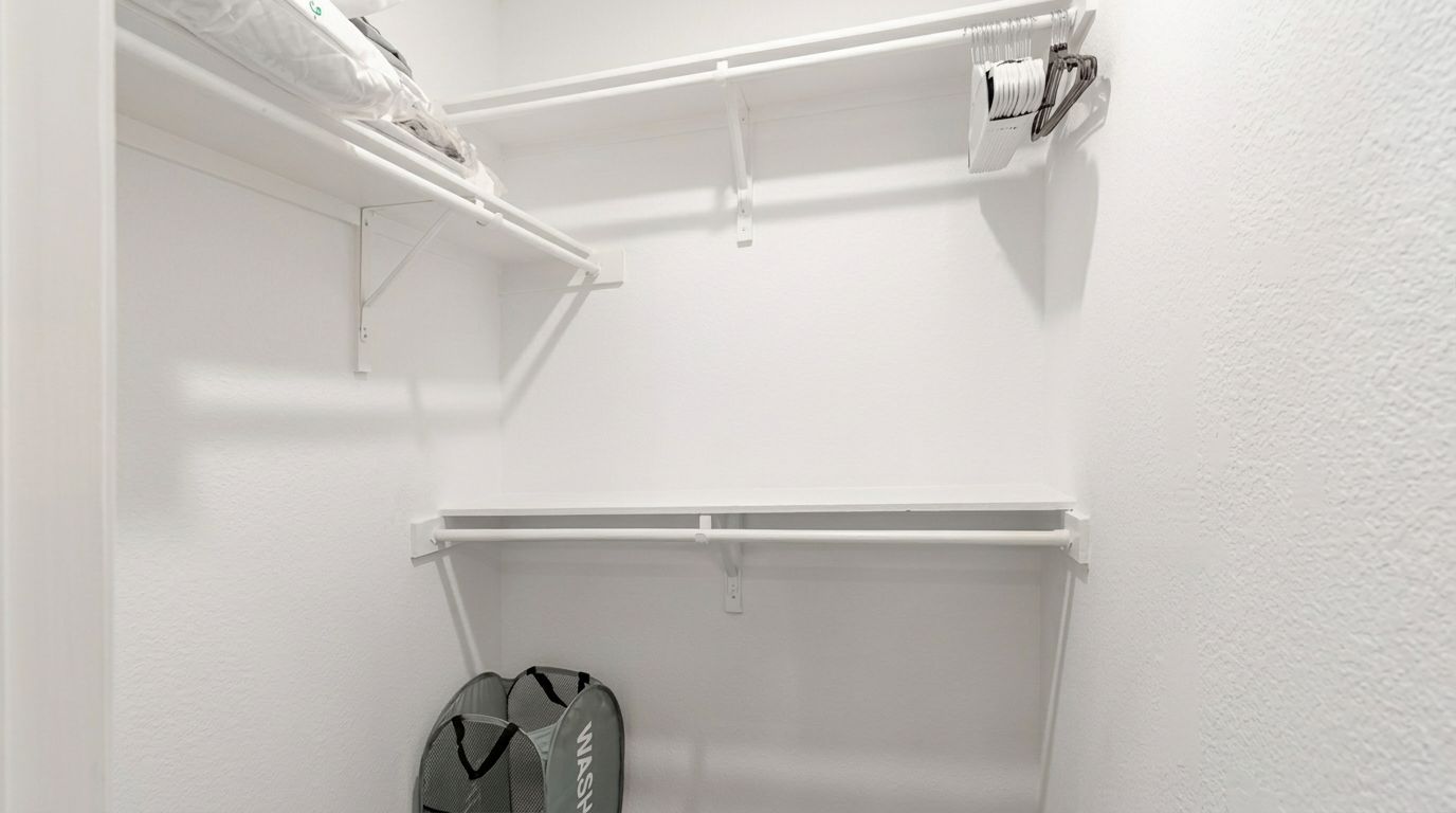 Un placard blanc avec une tringle pour suspendre les vêtements et un porte-chaussures.