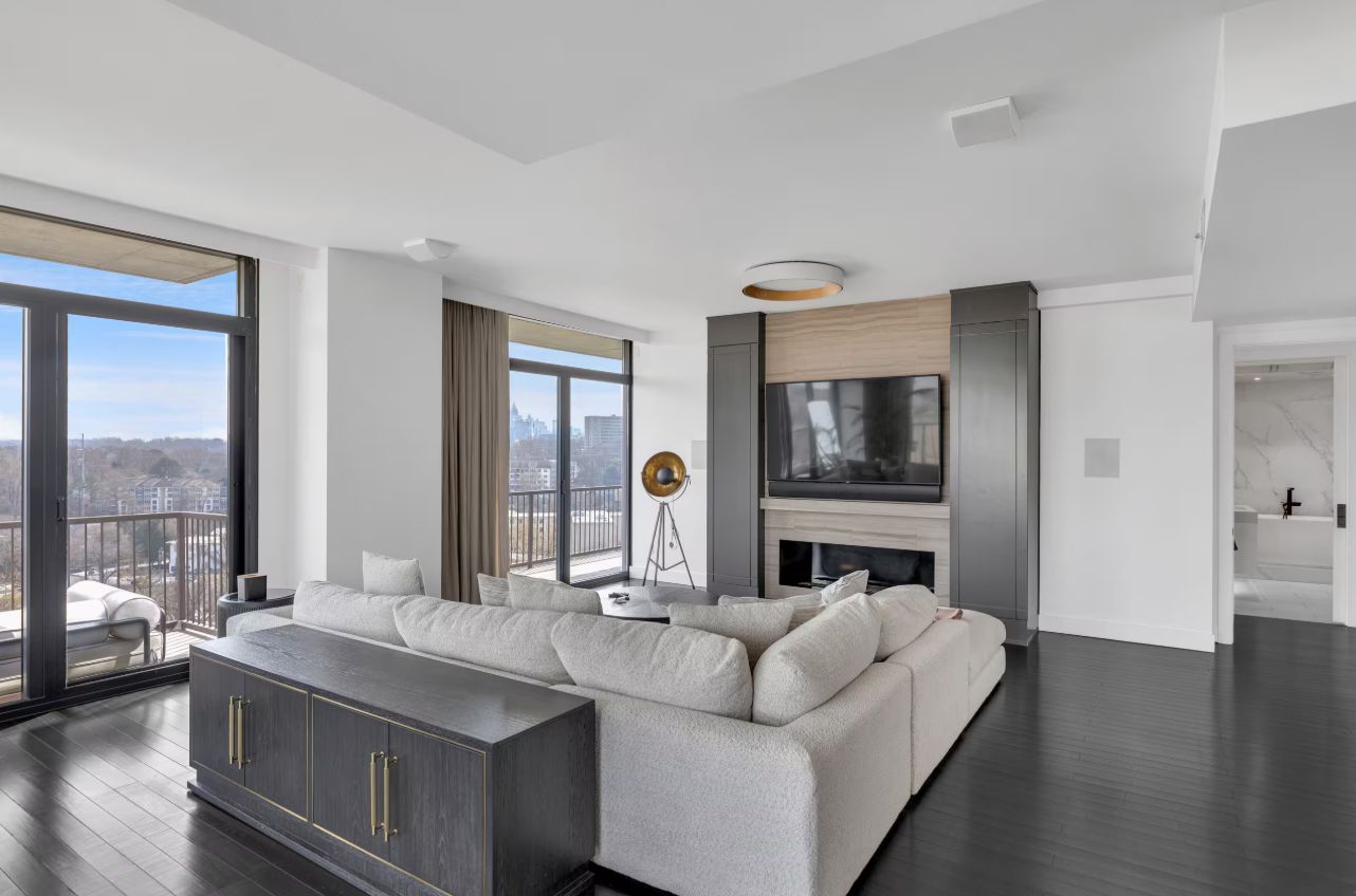 A modern living room with a large sectional sofa, a flat-screen TV, and a fireplace.