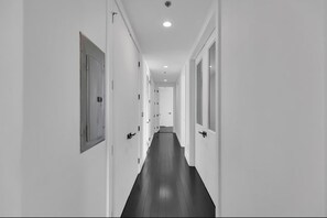 A long, narrow hallway with doors on both sides, leading to a room at the end. - Lovely XL Rare Penthouse, Master Spa Bedroom, 3 Balconies & More (Atlanta)