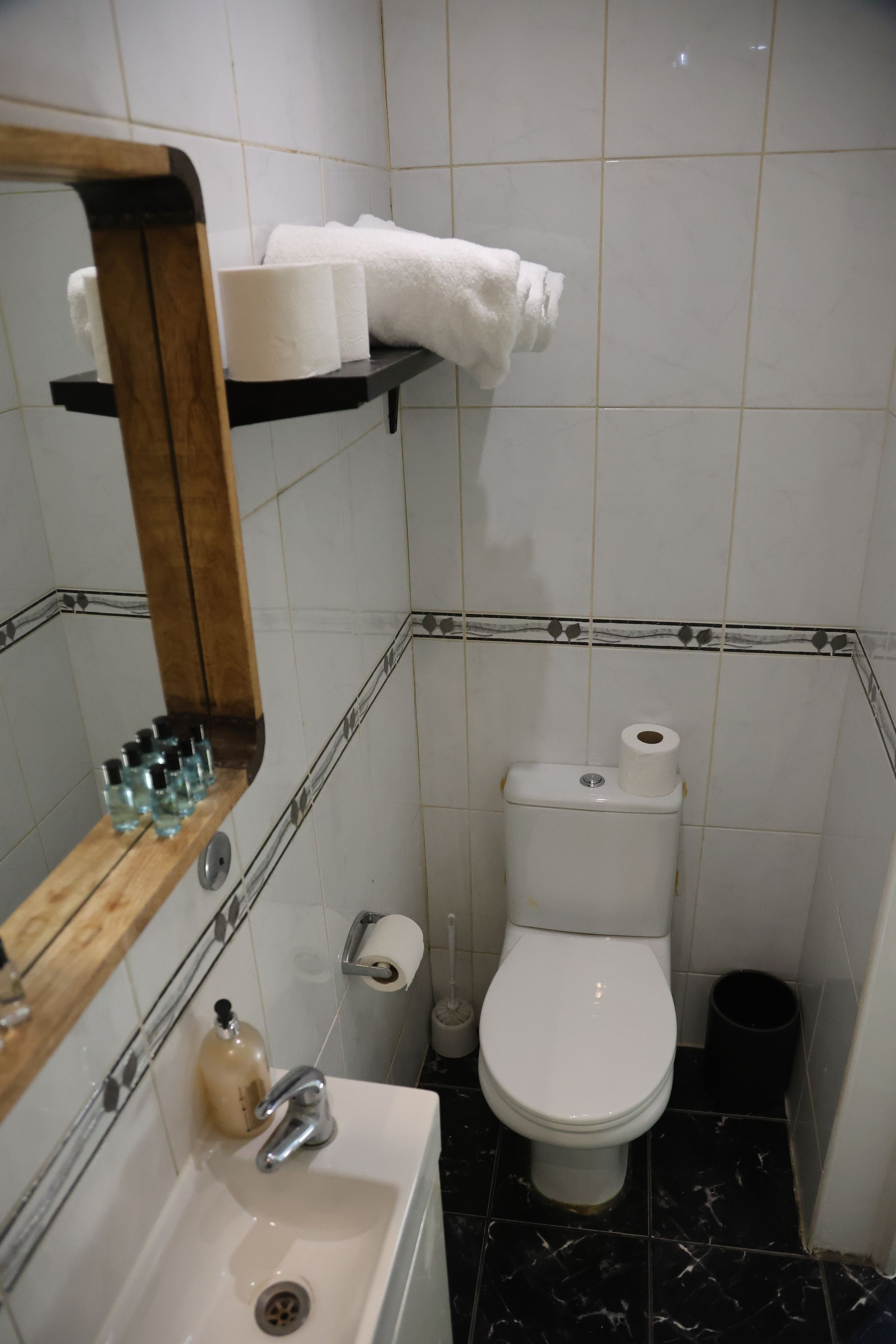 A bathroom with a toilet, sink, and mirror.