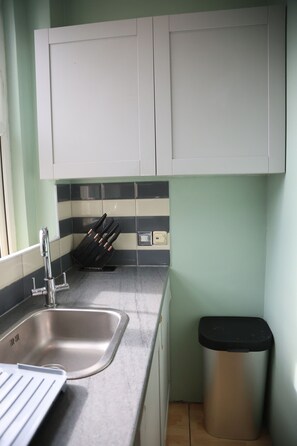 A kitchen with a stainless steel sink, a knife block, and a trash bin. - The Good Vibe (London)