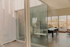 A modern interior with a glass door leading to a patio area. - Quail Springs Ranch | Pool & Spa (Joshua Tree)