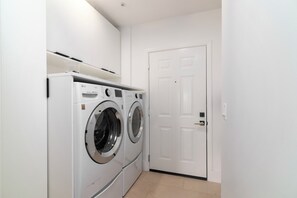 A laundry room with two white LG Direct Drive washing machines and a white door. - The Fairway House Scottsdale (Scottsdale)