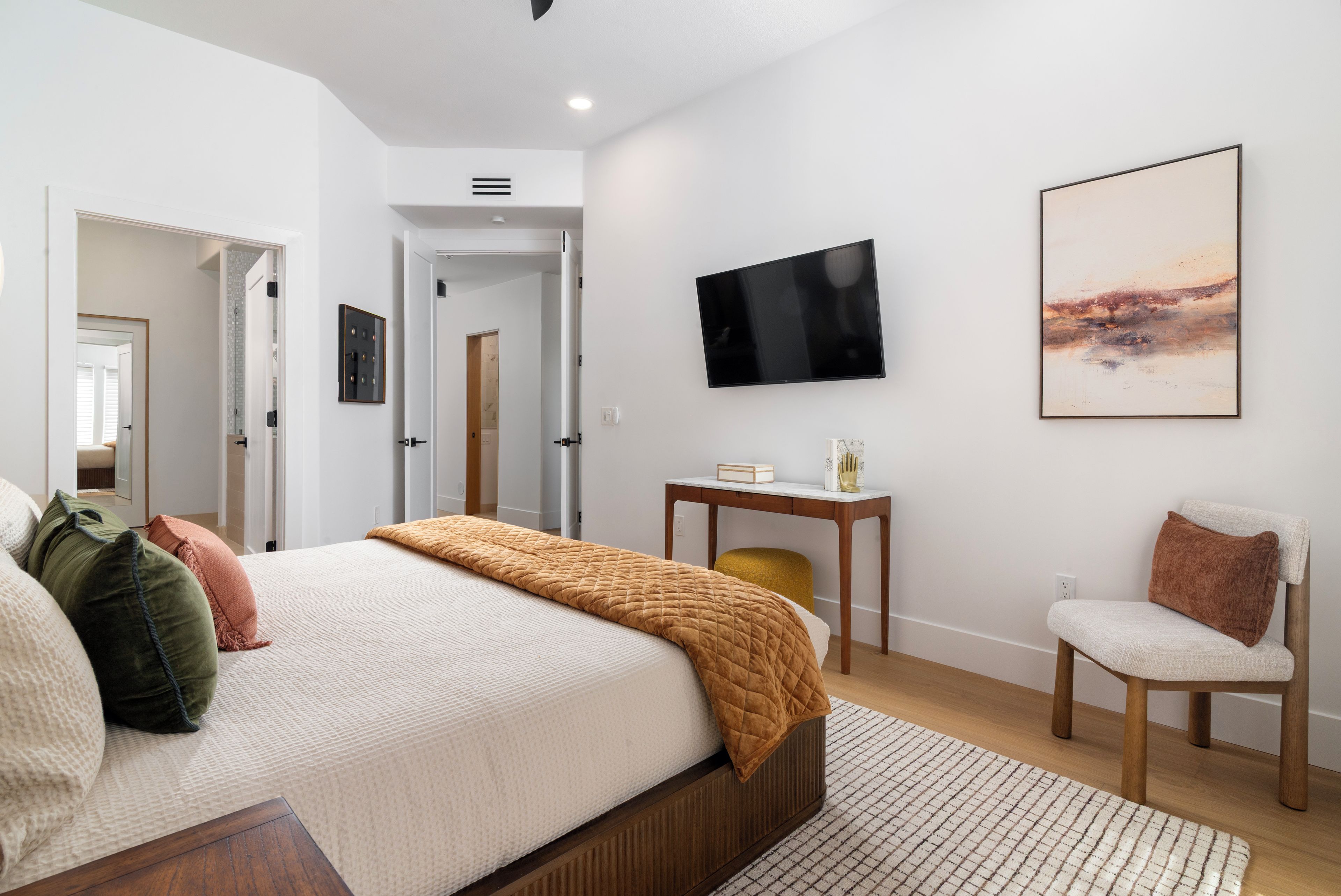 Un dormitorio moderno con cama, mesita de noche, silla y una obra de arte.