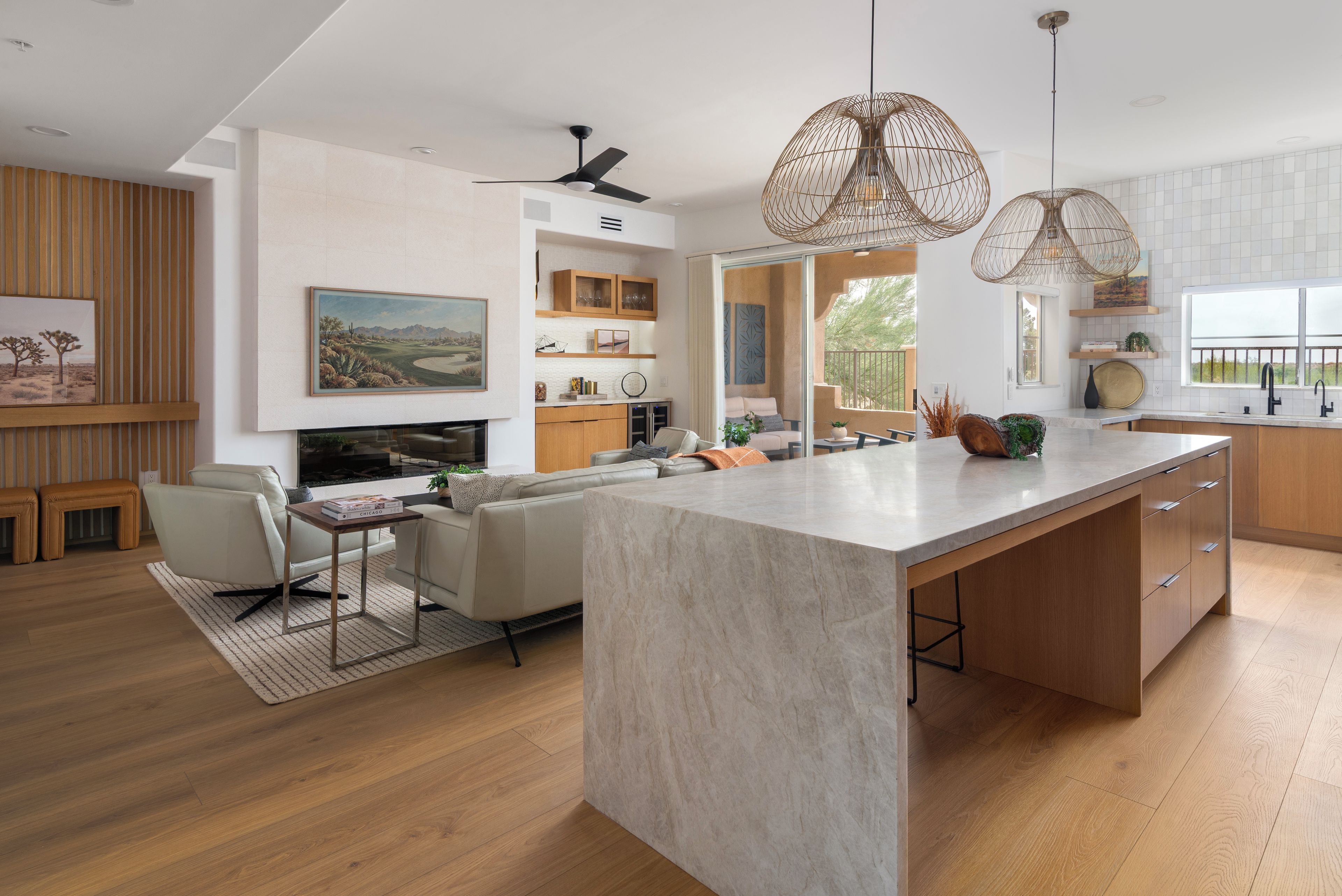 A modern kitchen with a large island, wooden cabinetry, and pendant lighting.