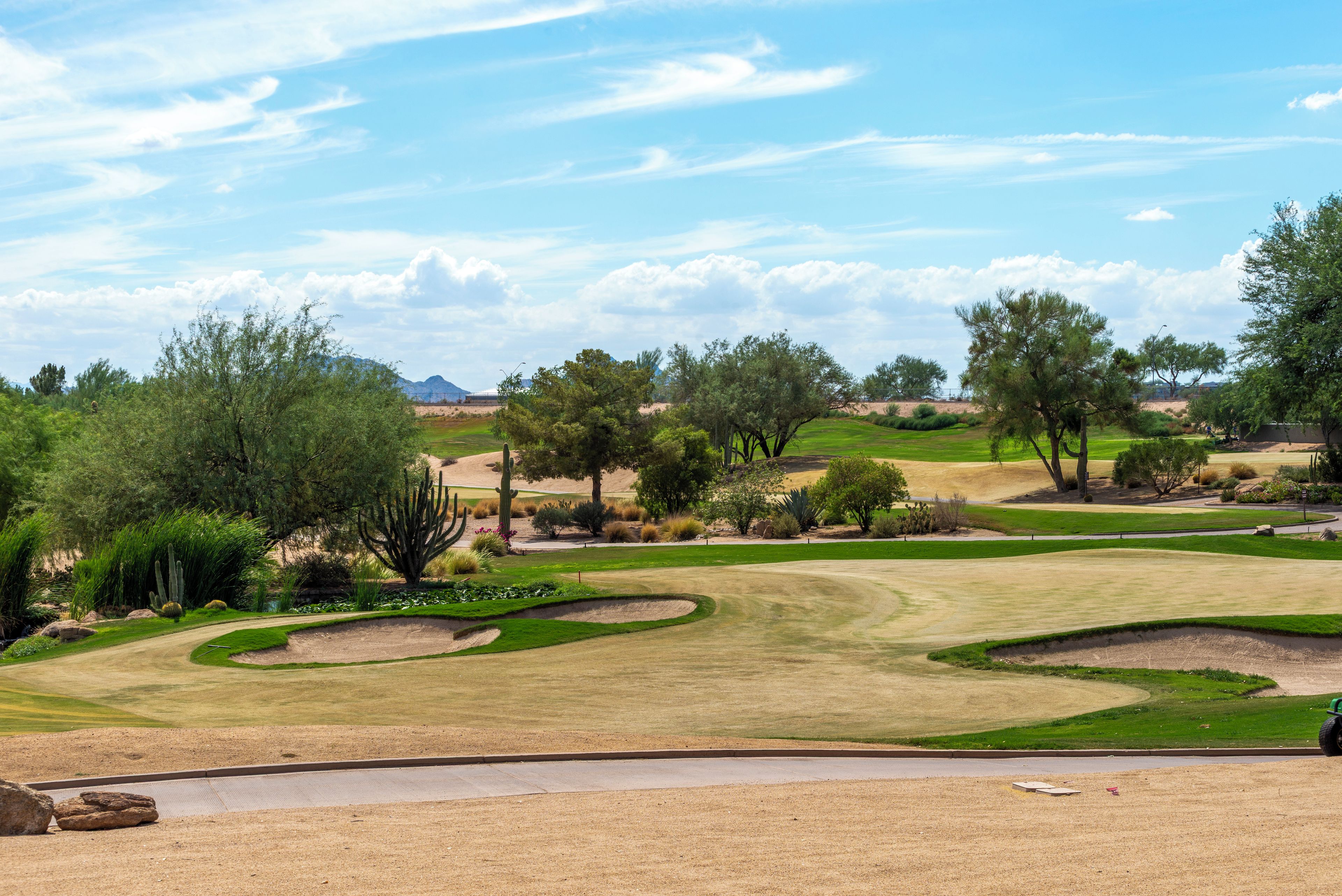 Un campo de golf con múltiples greens, búnkeres de arena y una diversidad de árboles y arbustos.