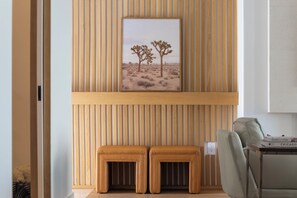 A room with a wooden slat wall, a framed desert landscape painting, and a pair of ottomans. - The Fairway House Scottsdale (Scottsdale)