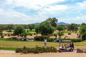 A golf course with a pond, cacti, and a golf cart. - The Fairway House Scottsdale (Scottsdale)